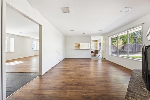 unfurnished living room with built in shelves, a wealth of natural light, and dark hardwood / wood-style floors