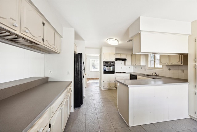 kitchen featuring kitchen peninsula, sink, backsplash, and black appliances