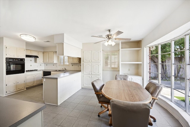 kitchen with sink, kitchen peninsula, decorative backsplash, light tile patterned floors, and black appliances