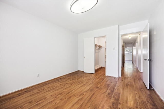 unfurnished bedroom with hardwood / wood-style floors, a spacious closet, and a closet