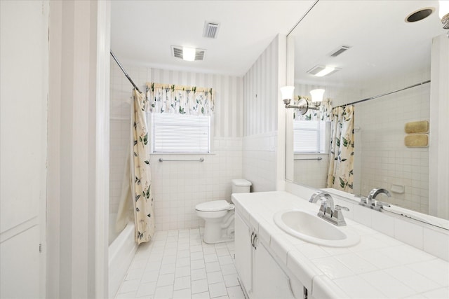 full bathroom with tile patterned floors, vanity, shower / bathtub combination with curtain, tile walls, and toilet