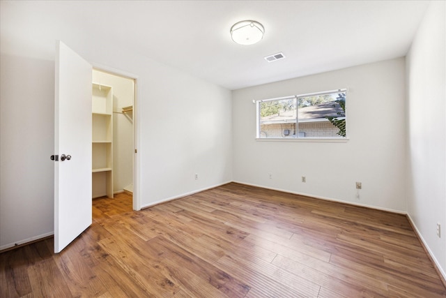 unfurnished bedroom featuring a walk in closet, a closet, and hardwood / wood-style floors