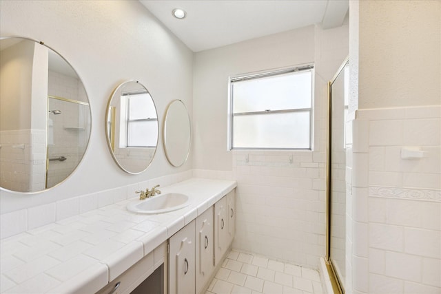 bathroom featuring tile patterned flooring, vanity, tiled shower, and tile walls