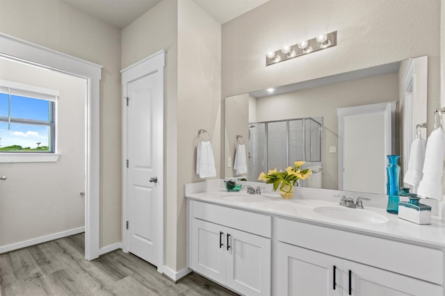 bathroom with hardwood / wood-style flooring, vanity, and a shower with shower door