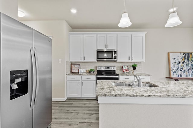 kitchen featuring pendant lighting, backsplash, white cabinets, sink, and appliances with stainless steel finishes