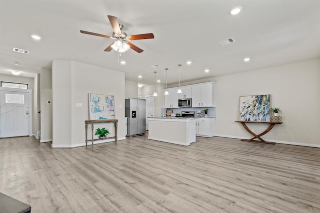 kitchen with hanging light fixtures, stainless steel appliances, a kitchen island, light hardwood / wood-style flooring, and white cabinets