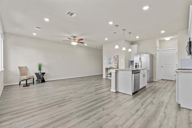 kitchen with white cabinets, pendant lighting, ceiling fan, and an island with sink