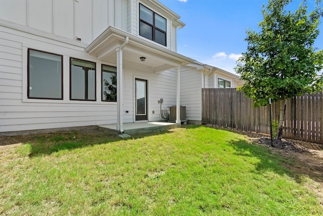 rear view of house with a lawn, a patio, and central AC unit