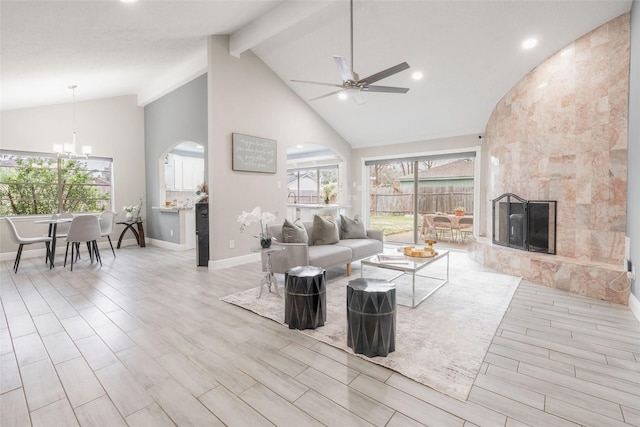 living room featuring a tile fireplace, beam ceiling, ceiling fan with notable chandelier, and high vaulted ceiling