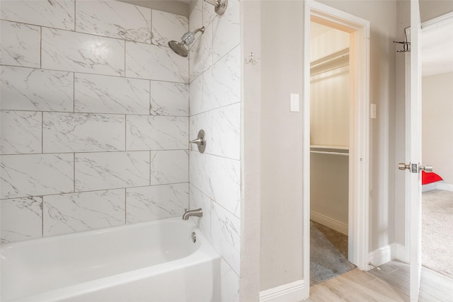 bathroom with hardwood / wood-style flooring and tiled shower / bath