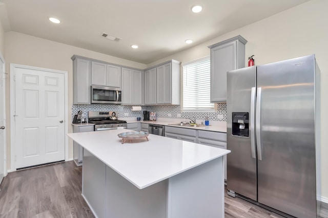 kitchen featuring a center island, light hardwood / wood-style flooring, stainless steel appliances, and sink