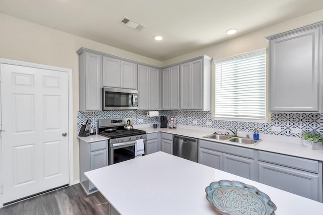 kitchen with gray cabinetry, dark hardwood / wood-style flooring, sink, and stainless steel appliances