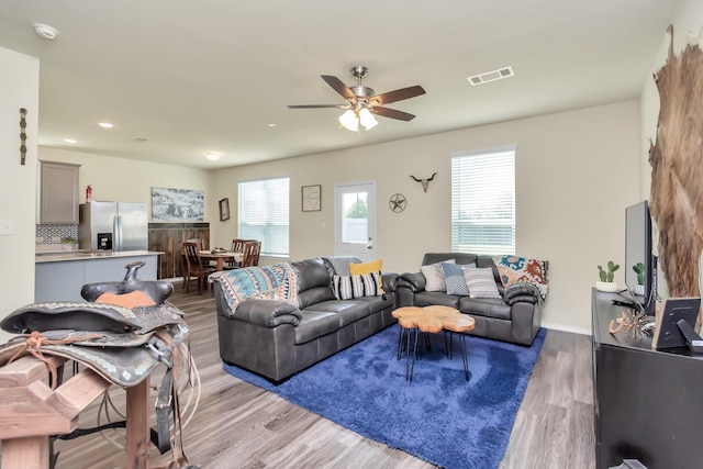 living room featuring a wealth of natural light, ceiling fan, and light hardwood / wood-style flooring