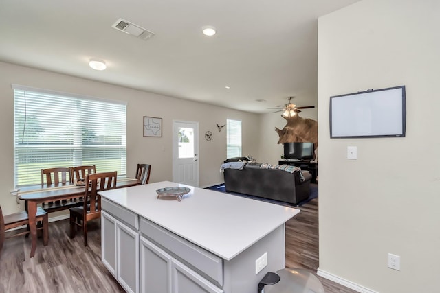 kitchen featuring ceiling fan, a kitchen island, a healthy amount of sunlight, and dark wood-type flooring