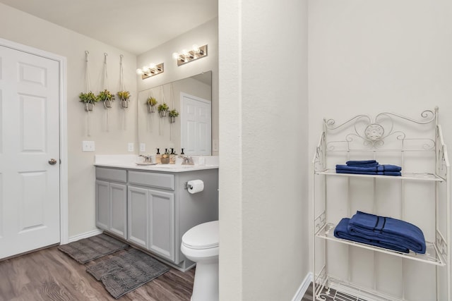 bathroom with hardwood / wood-style floors, vanity, and toilet