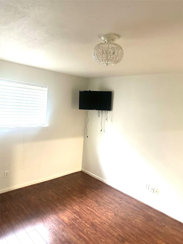 spare room with dark hardwood / wood-style flooring and a notable chandelier