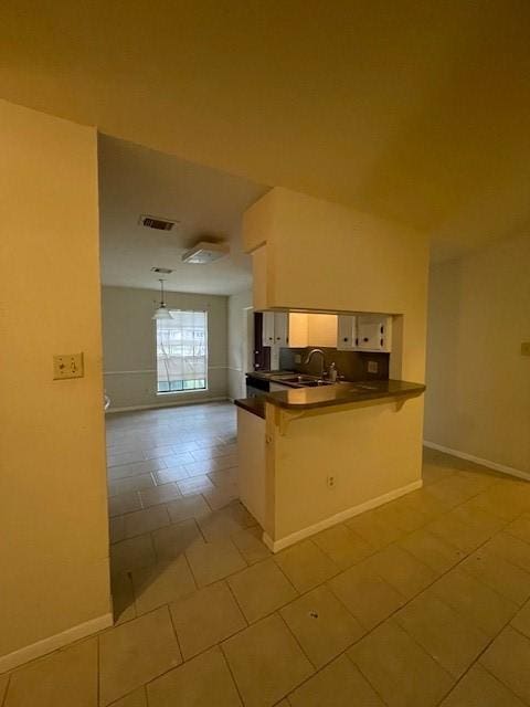 kitchen featuring kitchen peninsula, a kitchen breakfast bar, sink, light tile patterned floors, and hanging light fixtures