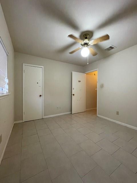 empty room with ceiling fan and light tile patterned flooring