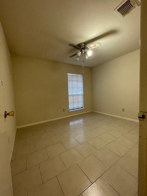 tiled spare room featuring ceiling fan