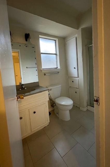 bathroom with tile patterned floors, vanity, a shower with shower door, and toilet