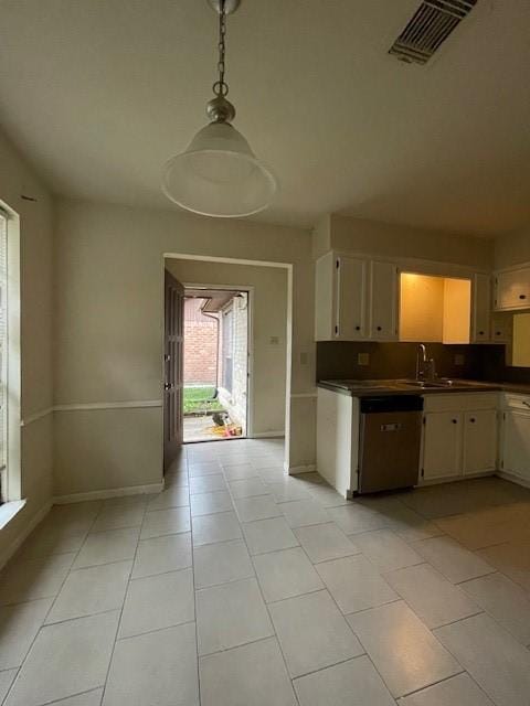 kitchen featuring light tile patterned floors, stainless steel dishwasher, hanging light fixtures, and sink