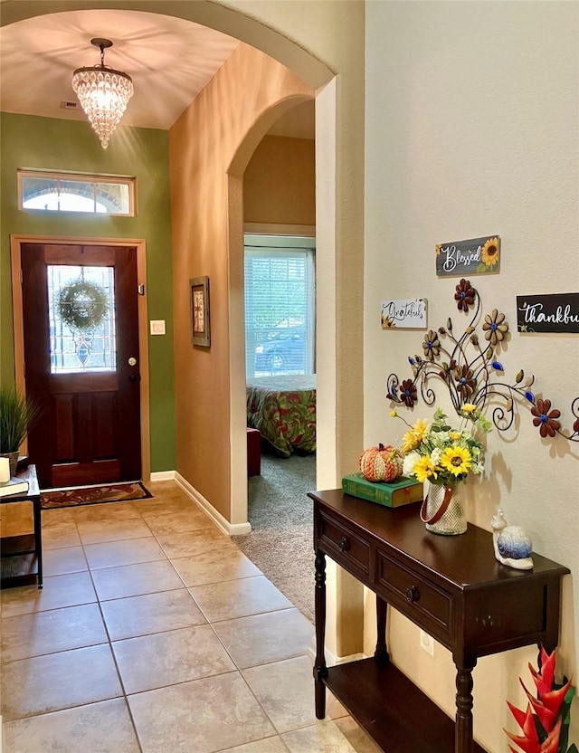 tiled foyer with an inviting chandelier