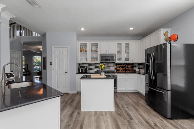 kitchen with sink, stainless steel appliances, a kitchen island, backsplash, and white cabinets