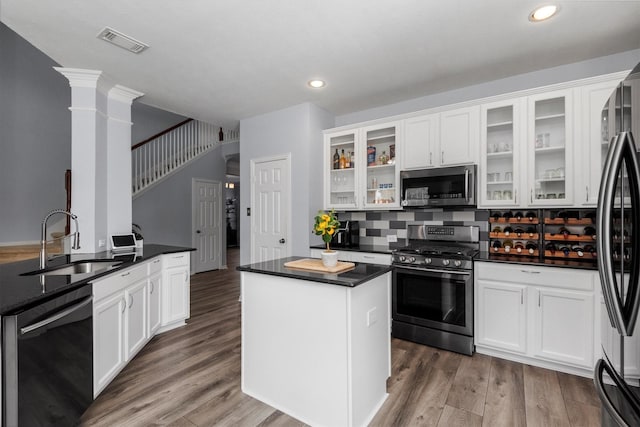 kitchen with white cabinets, stainless steel appliances, decorative columns, and sink