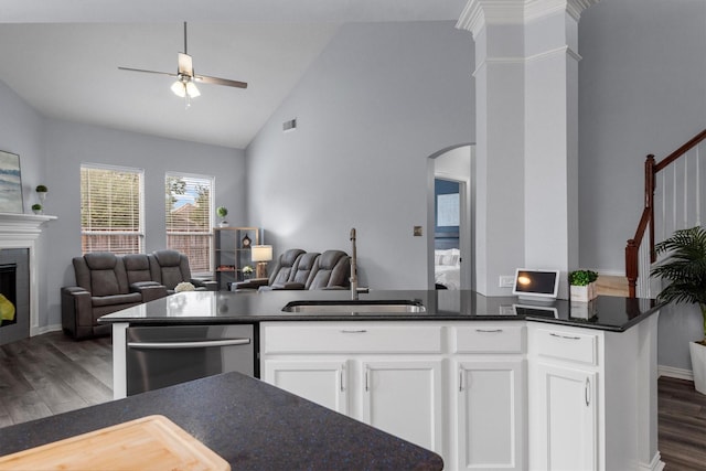 kitchen with stainless steel dishwasher, ceiling fan, sink, a tile fireplace, and white cabinets