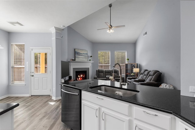 kitchen with white cabinetry, sink, light hardwood / wood-style flooring, stainless steel dishwasher, and vaulted ceiling