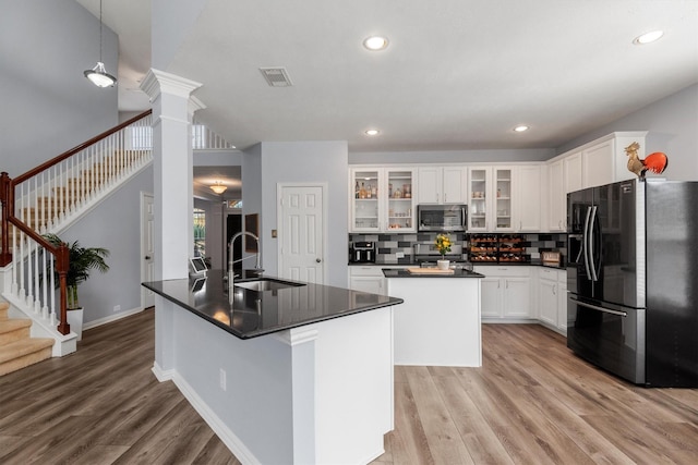 kitchen with sink, stainless steel appliances, decorative backsplash, a center island with sink, and white cabinets