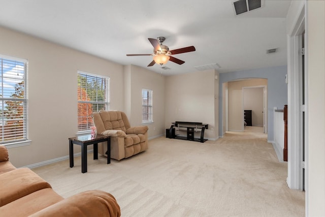 living area featuring plenty of natural light, ceiling fan, and light colored carpet