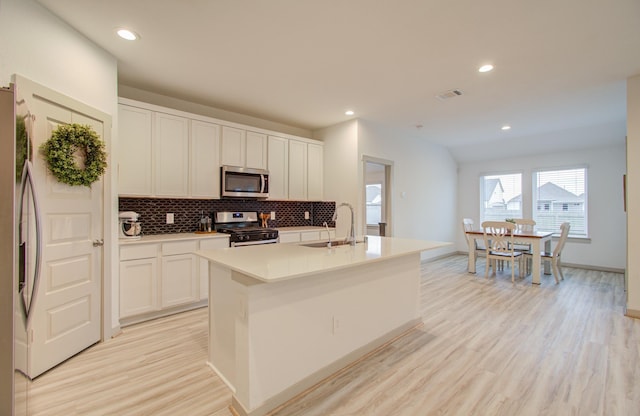 kitchen with white cabinetry, sink, a kitchen island with sink, appliances with stainless steel finishes, and light wood-type flooring