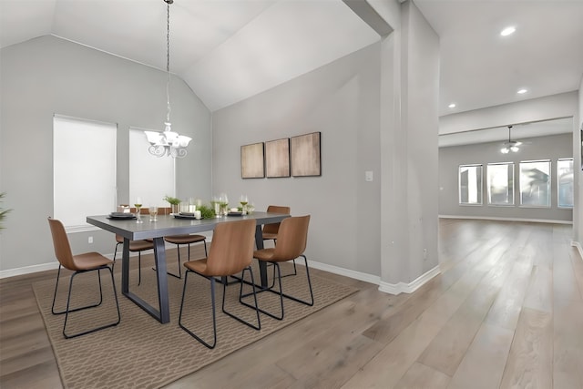 dining area featuring ceiling fan with notable chandelier, light hardwood / wood-style flooring, and lofted ceiling