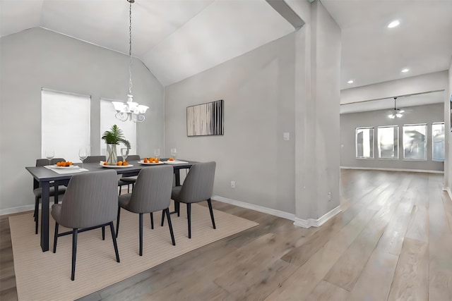 dining area featuring ceiling fan with notable chandelier, lofted ceiling, and light hardwood / wood-style flooring