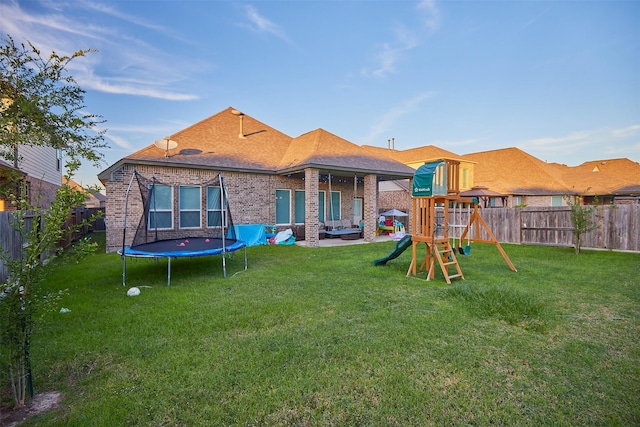 back of house with a playground, a yard, a trampoline, and a patio