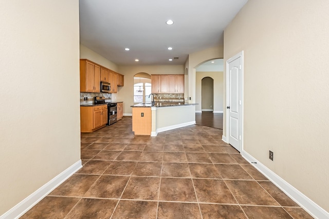 kitchen with decorative backsplash, sink, a kitchen island with sink, and appliances with stainless steel finishes