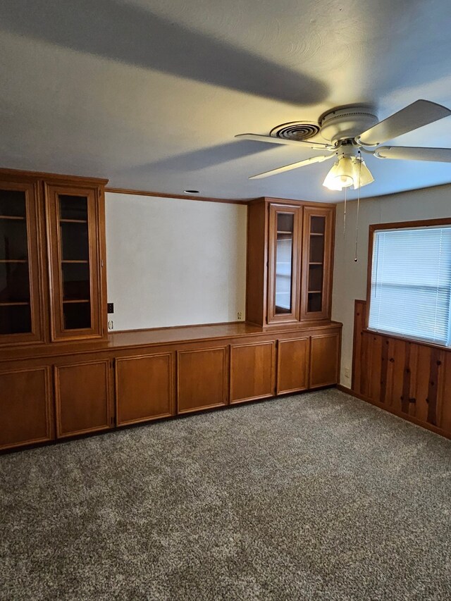 carpeted empty room featuring ceiling fan and wood walls