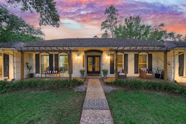 ranch-style home featuring a yard and french doors