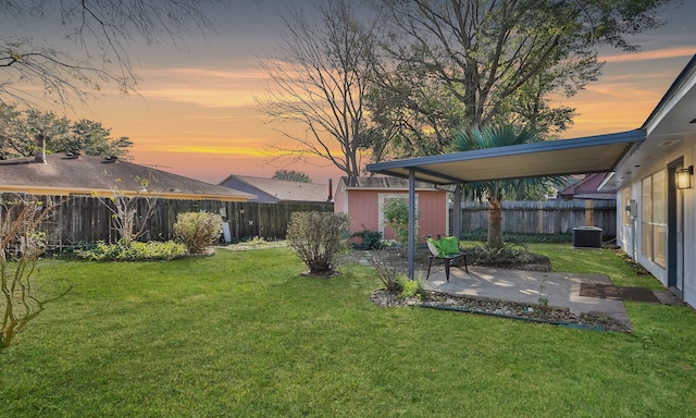 yard at dusk with a patio and central air condition unit