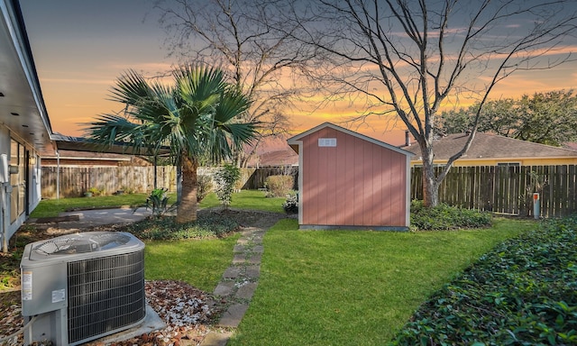 yard at dusk with central AC unit and a storage unit