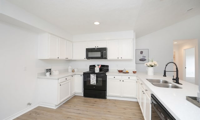 kitchen featuring light wood-type flooring, vaulted ceiling, sink, black appliances, and white cabinetry