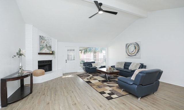 living room featuring high vaulted ceiling, ceiling fan, a fireplace, beamed ceiling, and light hardwood / wood-style floors