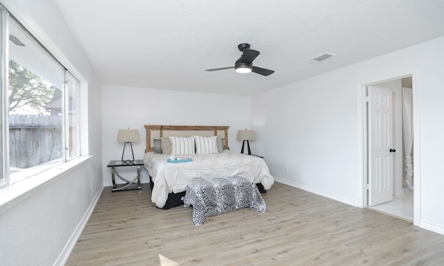 bedroom with ceiling fan, light wood-type flooring, and multiple windows