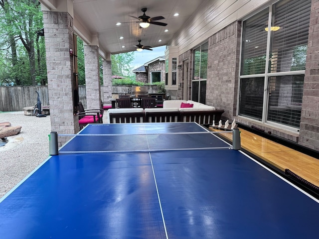 game room featuring ceiling fan and wood walls