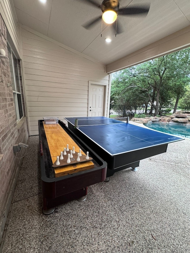 game room featuring ceiling fan, brick wall, and vaulted ceiling