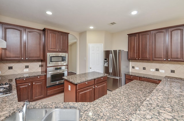 kitchen featuring sink, stone countertops, decorative backsplash, light tile patterned flooring, and appliances with stainless steel finishes