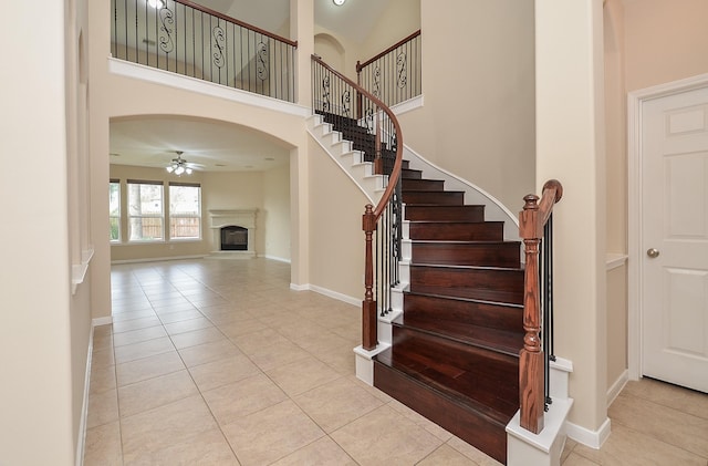 staircase with tile patterned floors, ceiling fan, and a high ceiling