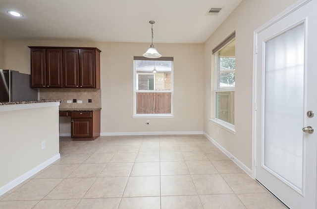 kitchen featuring backsplash, stainless steel fridge, decorative light fixtures, dark brown cabinets, and light tile patterned floors