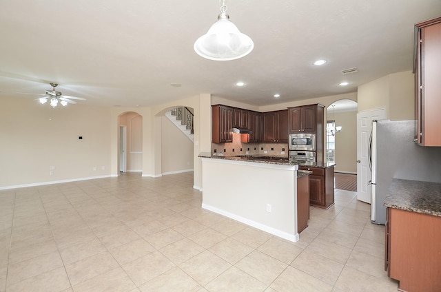 kitchen featuring pendant lighting, ceiling fan, decorative backsplash, appliances with stainless steel finishes, and dark brown cabinets